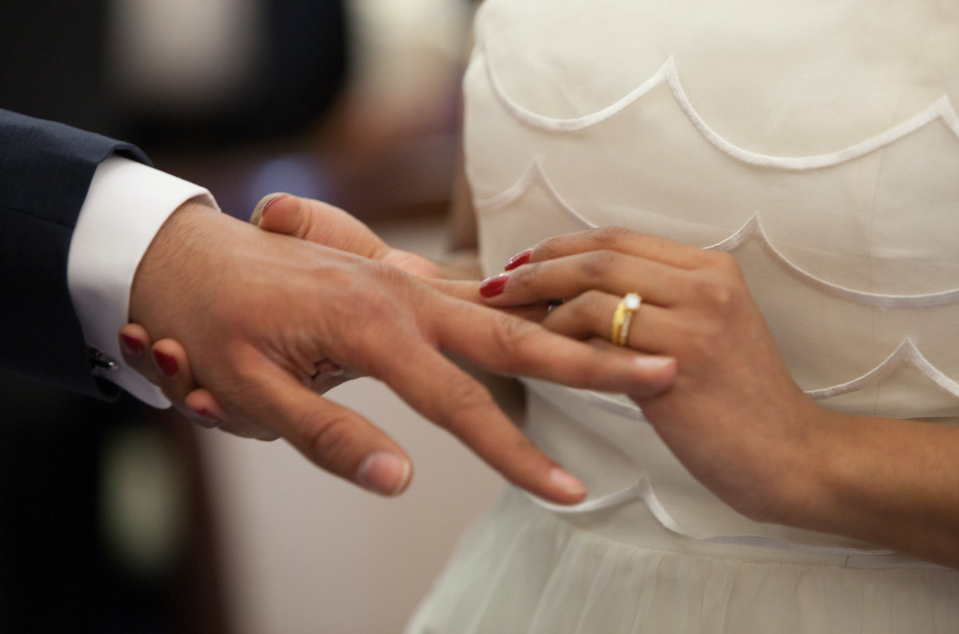 Close-up photo of a bride placing a wedding ring on the groom's finger.
